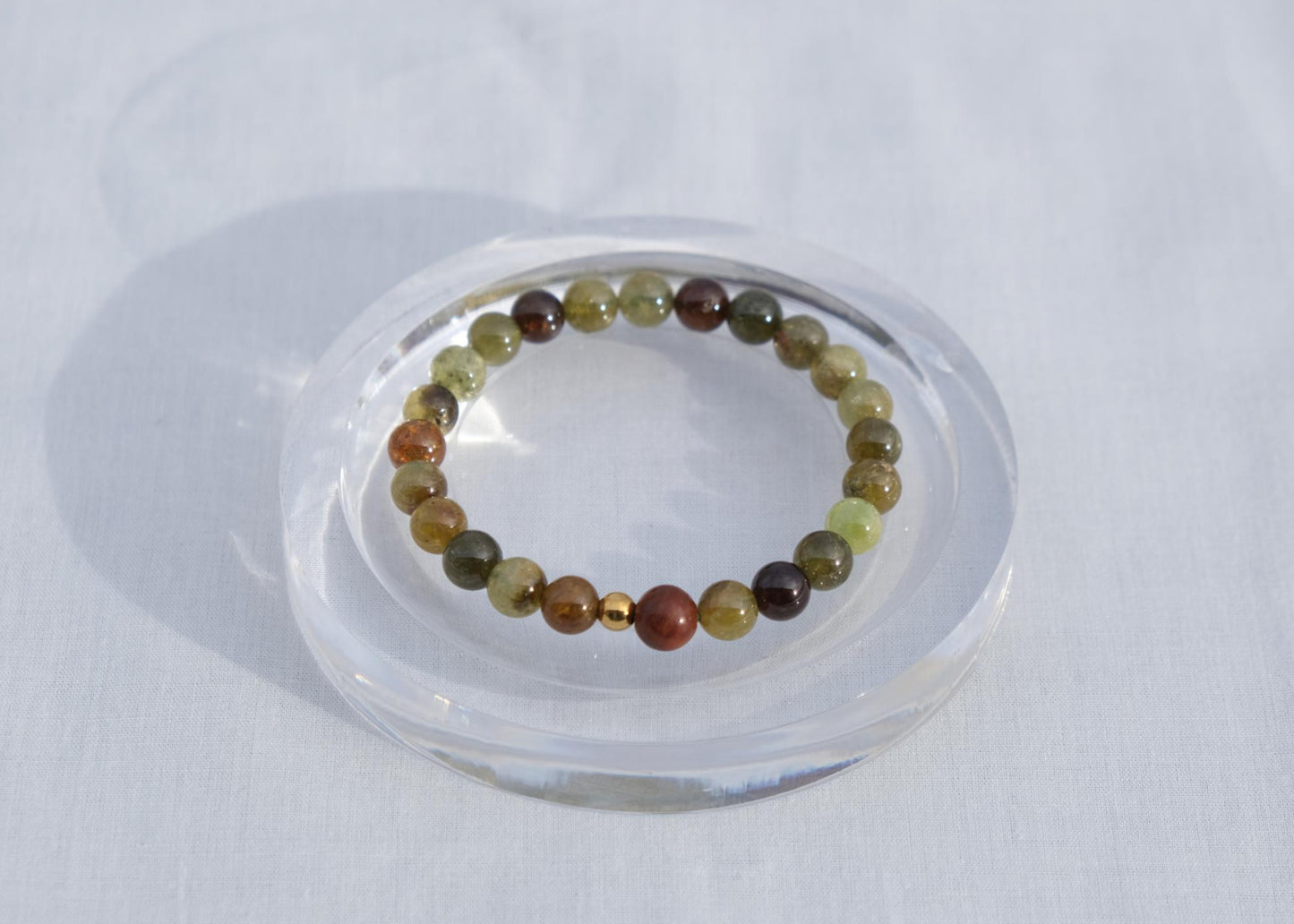 Multicolored beaded bracelet on a clear stand against a white background