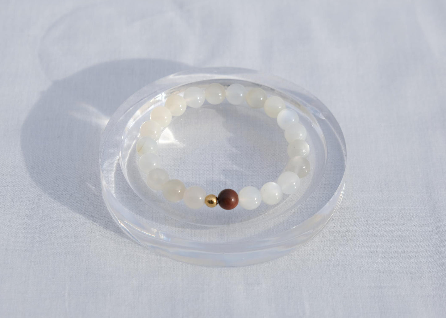 Bracelet with white beads and a brown bead on a white background