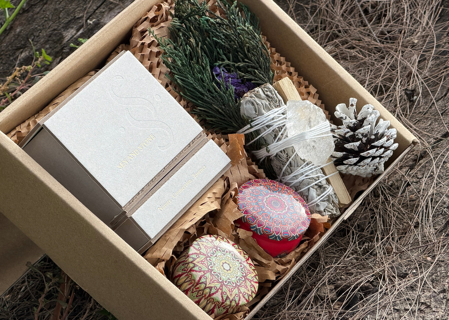 Box containing a notebook, incense sticks, and decorative items on a natural background