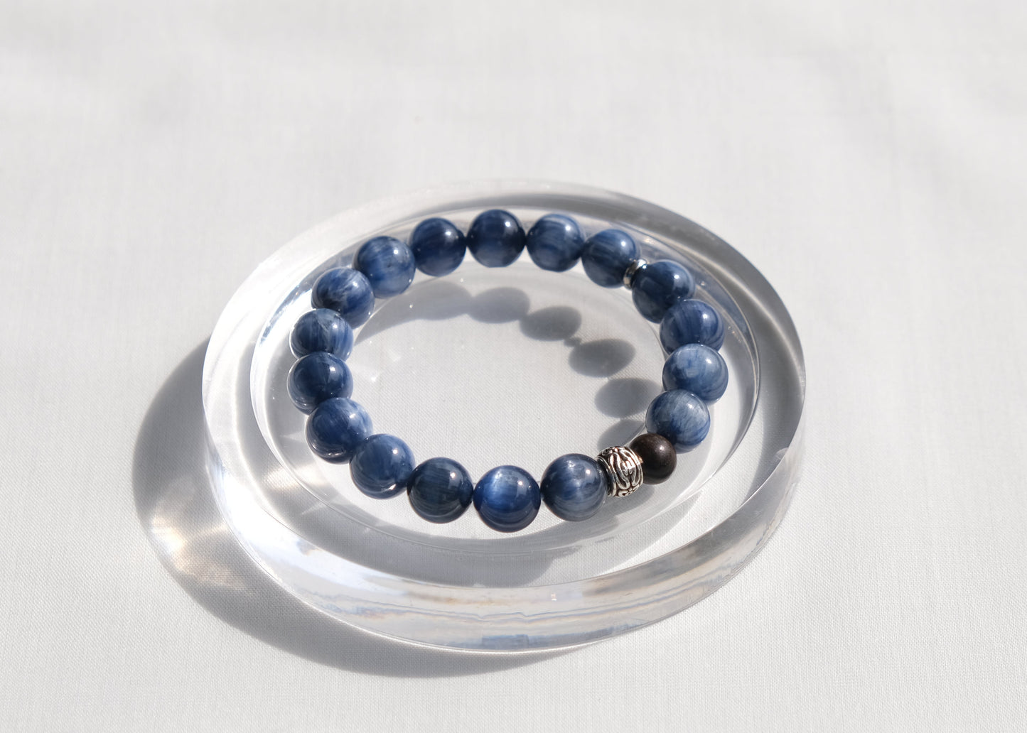 Blue beaded bracelet on a clear stand against a white background