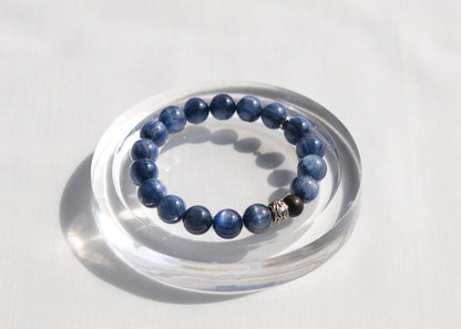 Blue beaded bracelet on a clear stand against a white background