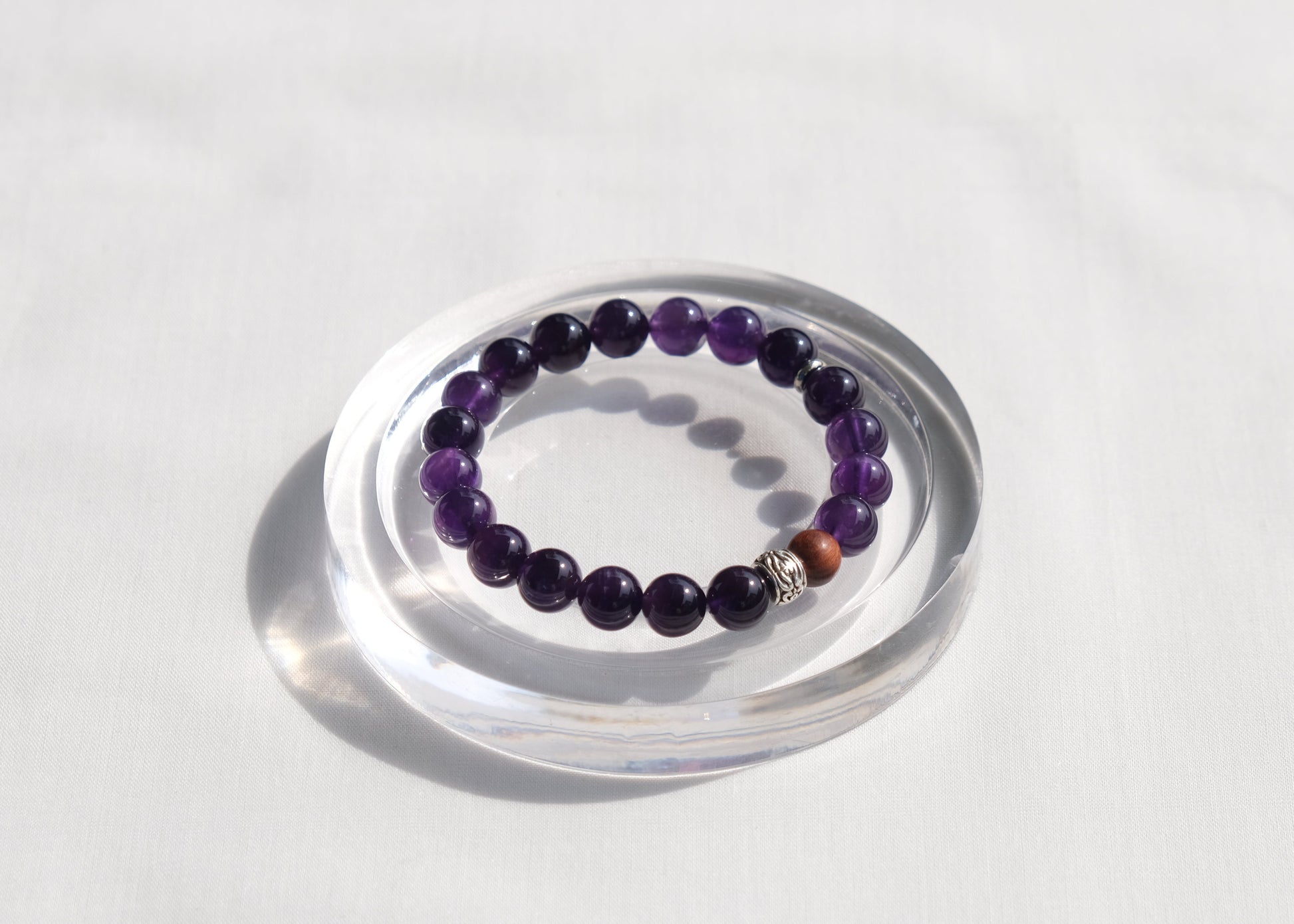 Purple beaded bracelet on a clear stand against a white background