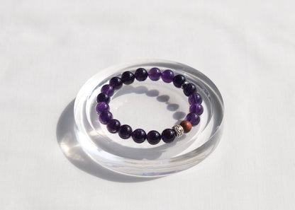 Purple beaded bracelet on a clear stand against a white background
