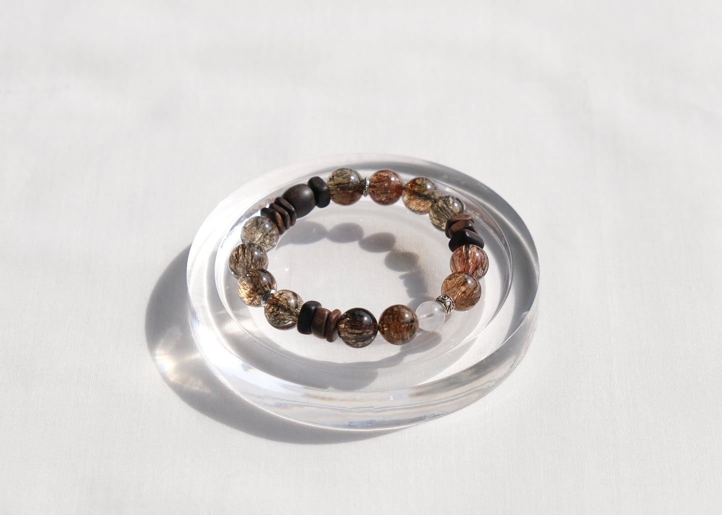 Bracelet with multicolored beads on a clear stand against a white background