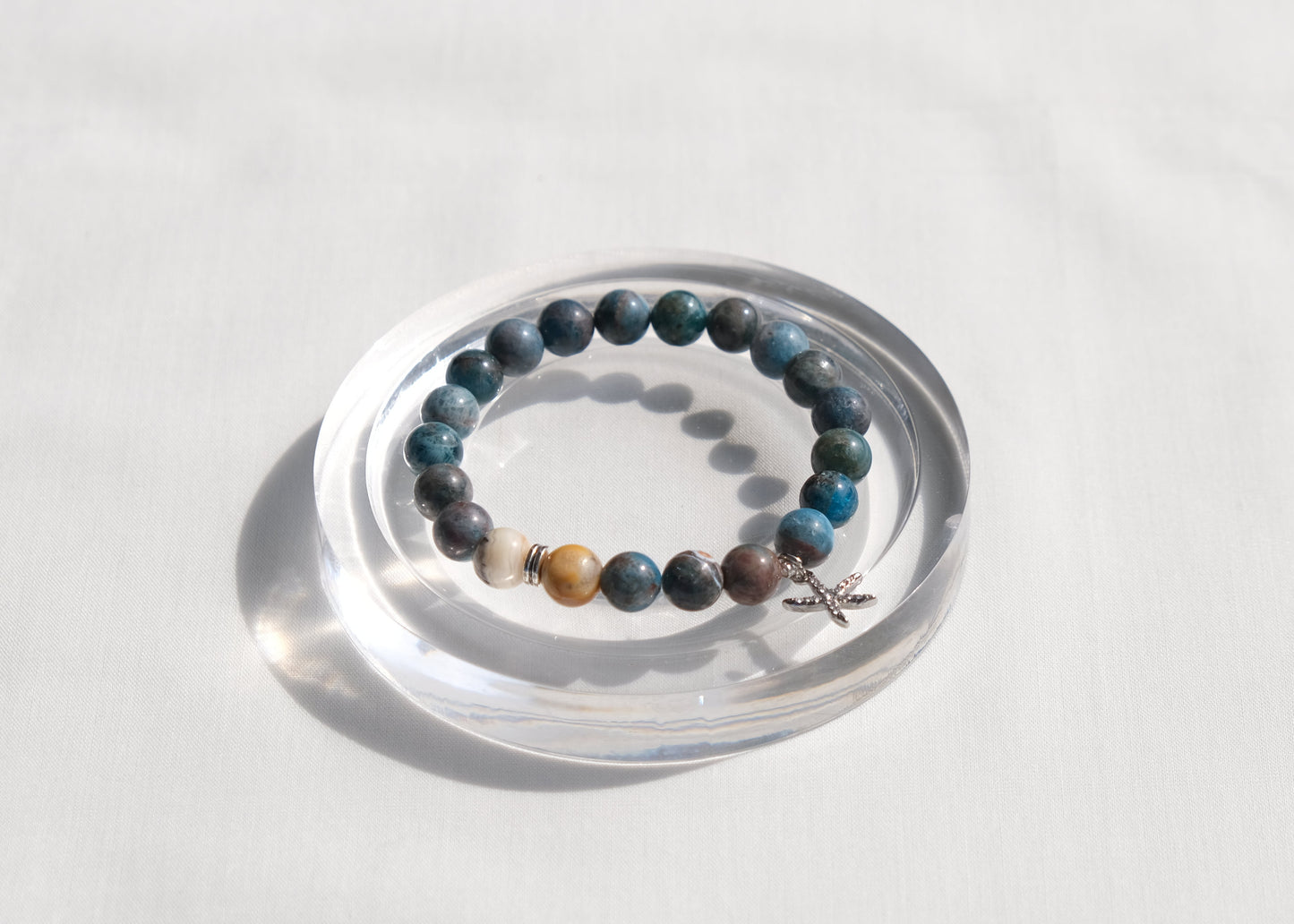 Beaded bracelet with star charm on a clear stand against a white background