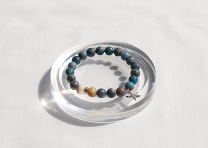 Beaded bracelet with star charm on a clear stand against a white background