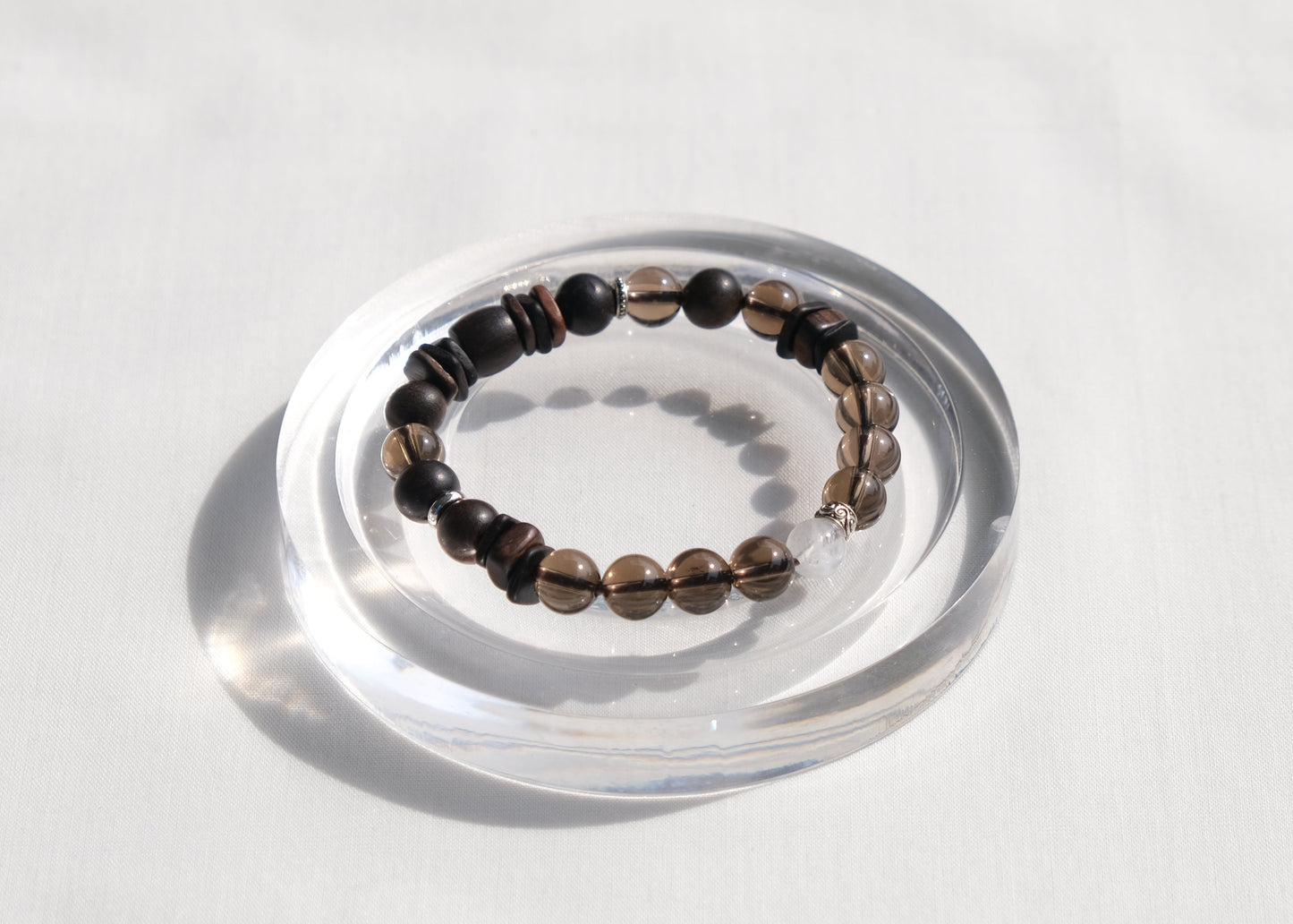 Bracelet on a clear circular stand against a light gray background