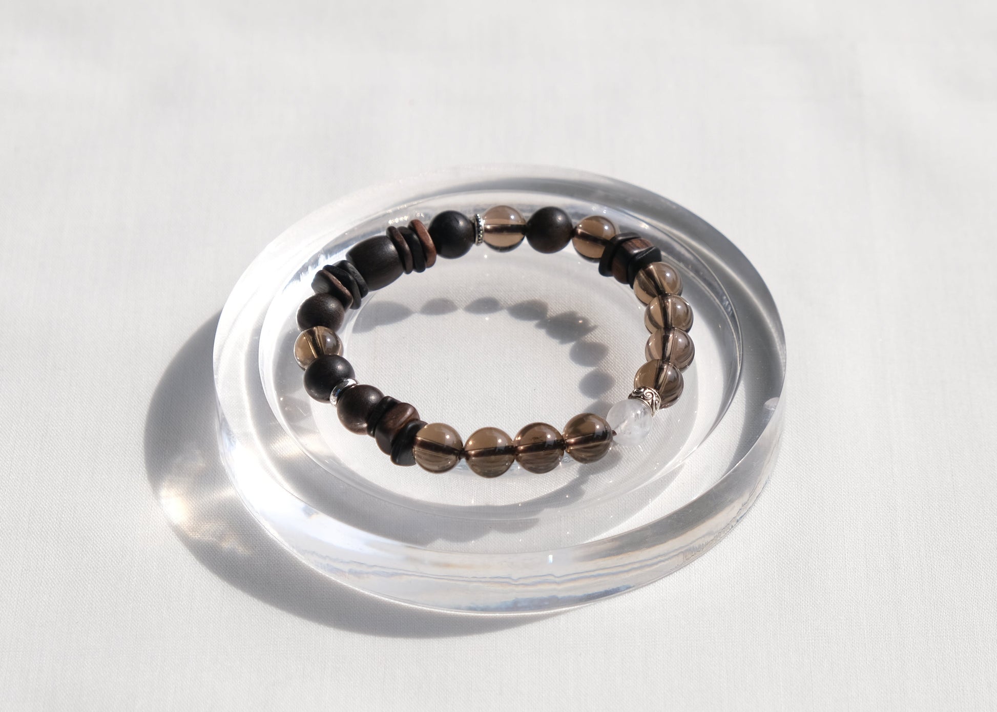 Bracelet on a clear circular stand against a light gray background