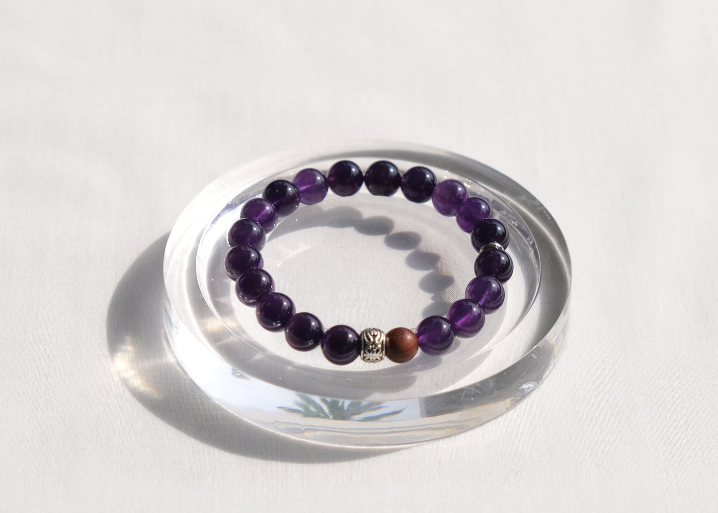 Amethyst beaded bracelet on a clear stand with a white background