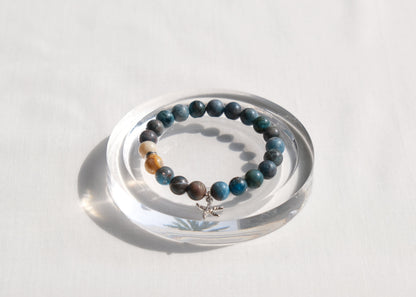 Stack of beaded bracelets on a clear circular stand against a white background