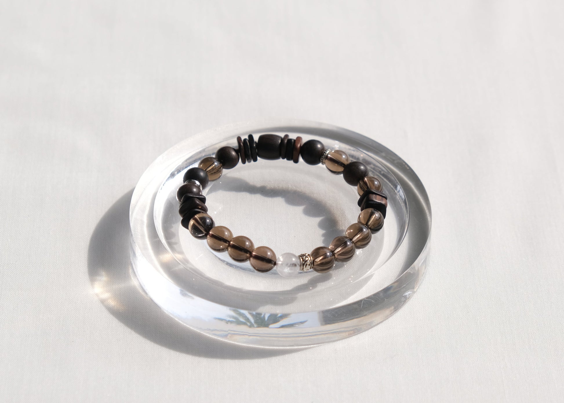 Bracelet with black and brown beads on a clear stand against a white background