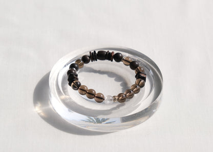 Bracelet with black and brown beads on a clear stand against a white background