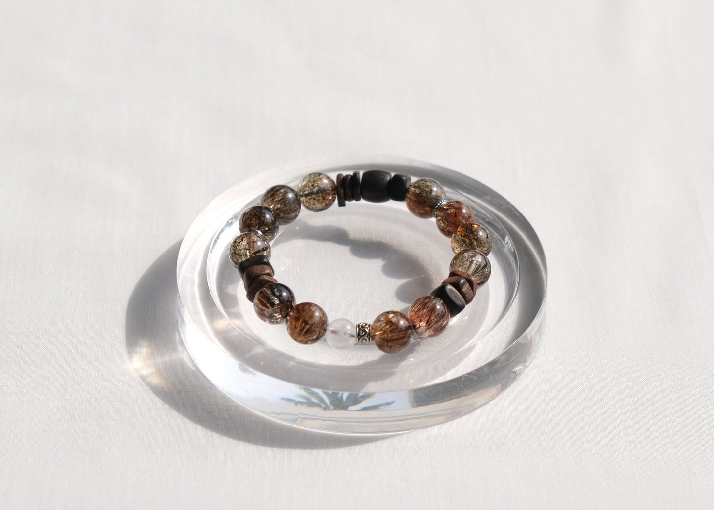 Multicolored beaded bracelet on a clear stand against a white background