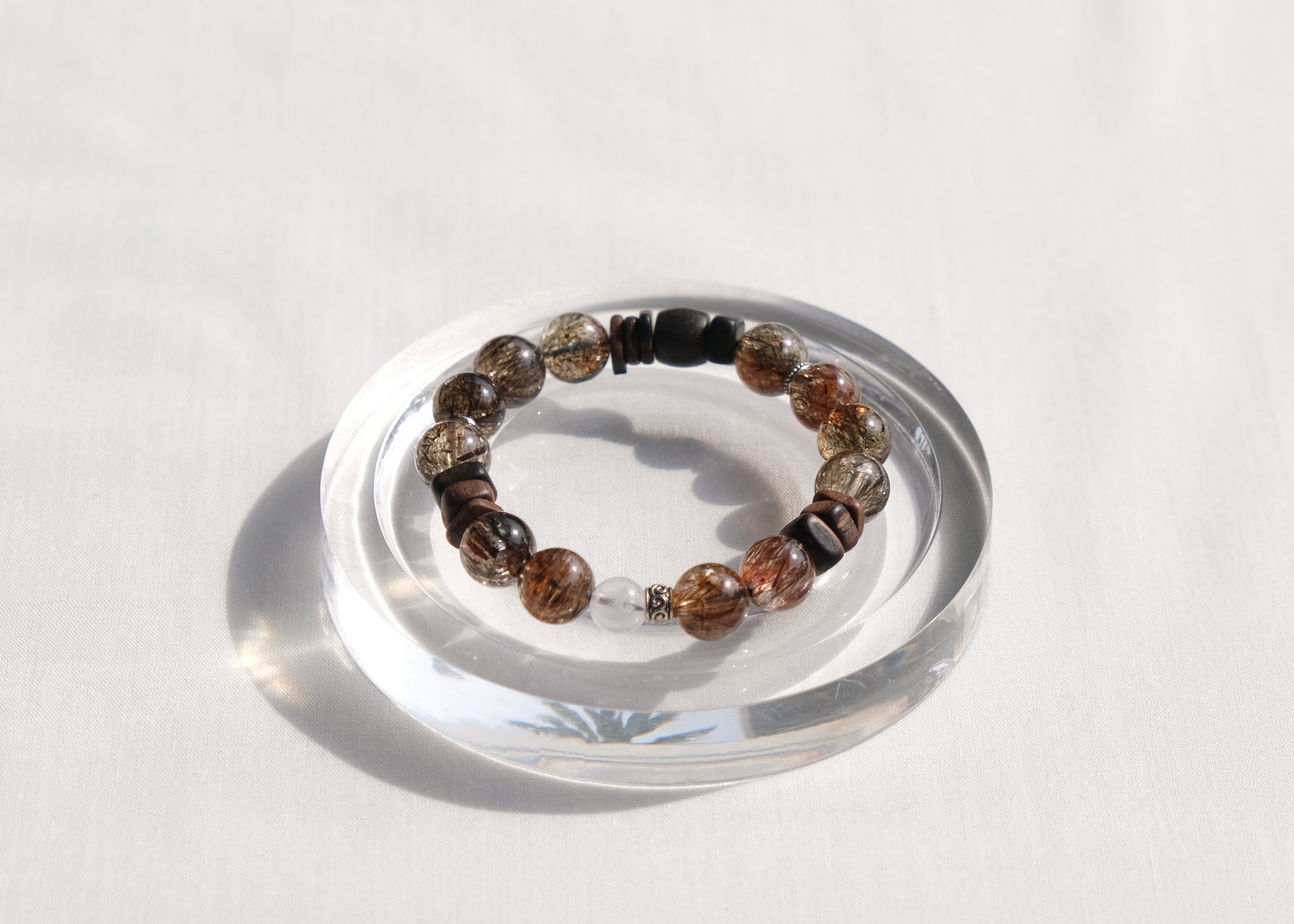 Multicolored beaded bracelet on a clear stand against a white background