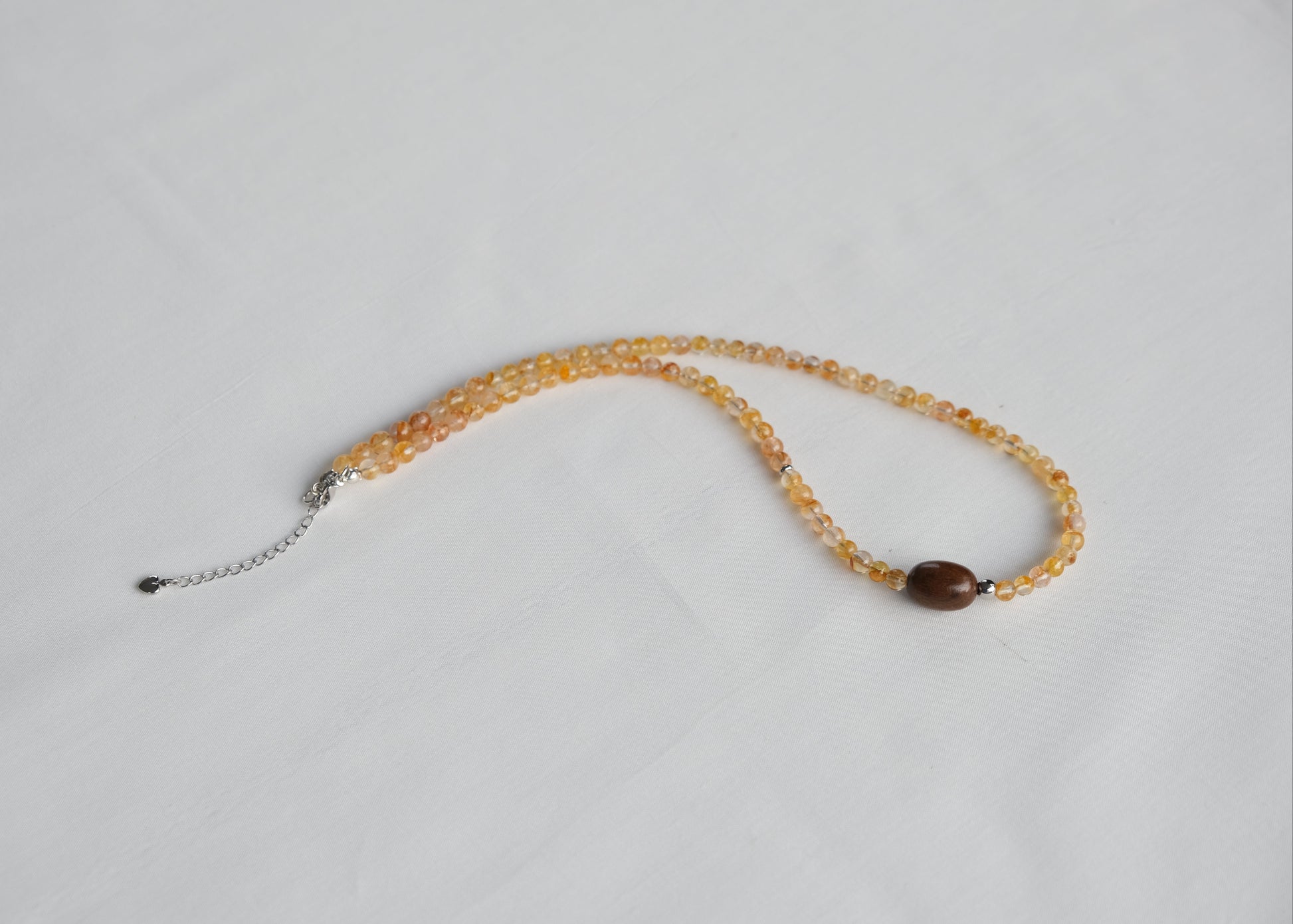 Necklace with yellow beads and a brown pendant on a light gray background