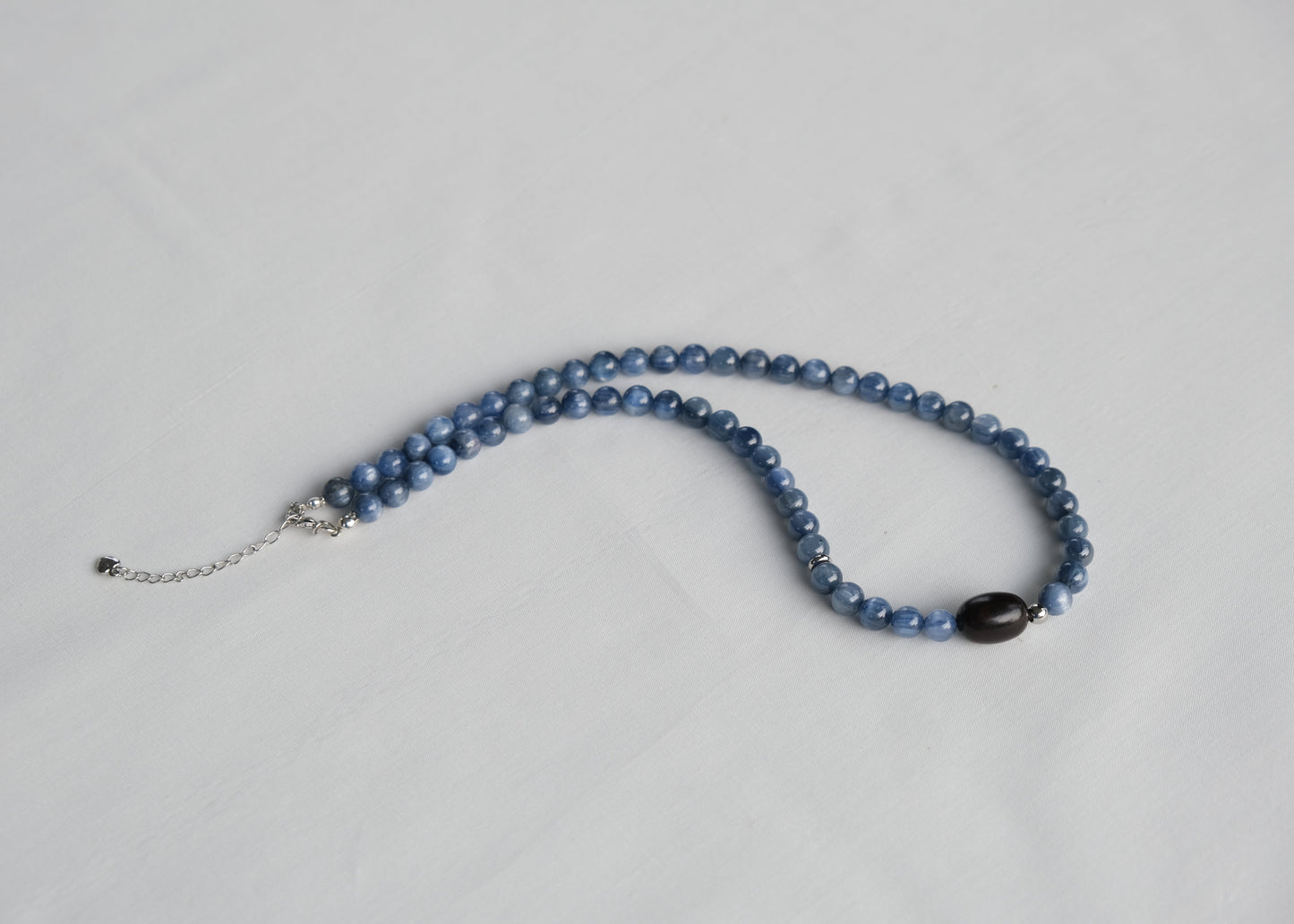 Blue beaded necklace on a light gray background