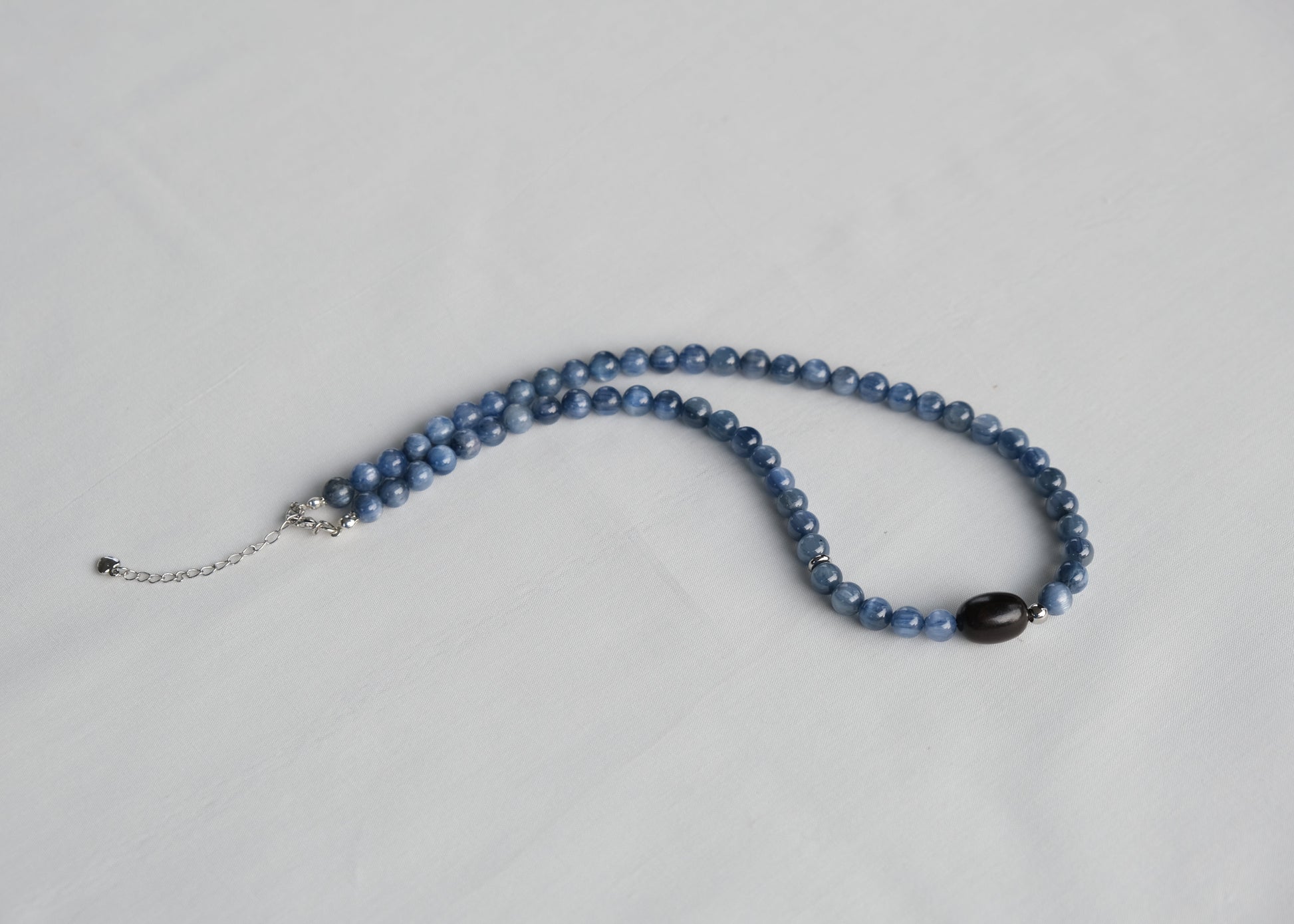 Blue beaded necklace on a light gray background