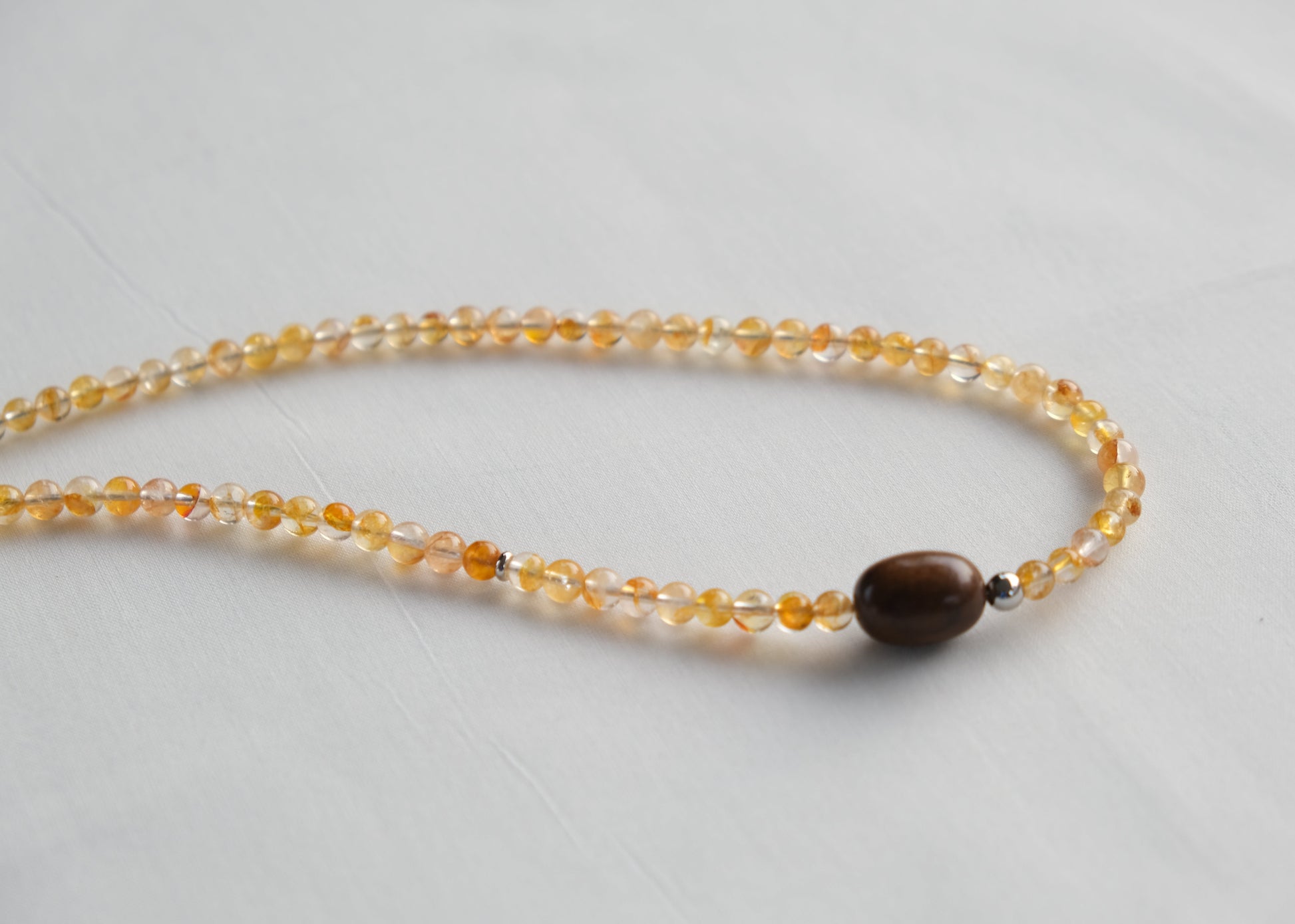Necklace with yellow beads and a brown bead on a light gray background