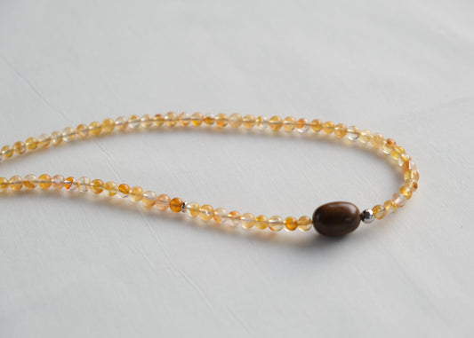 Necklace with yellow beads and a brown bead on a light gray background