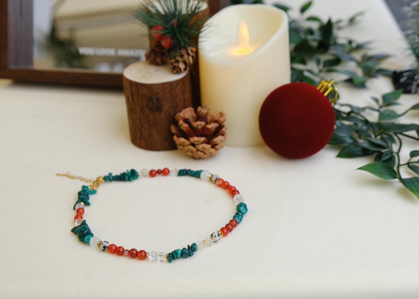 Colorful beaded necklace on a white surface with Christmas decorations.