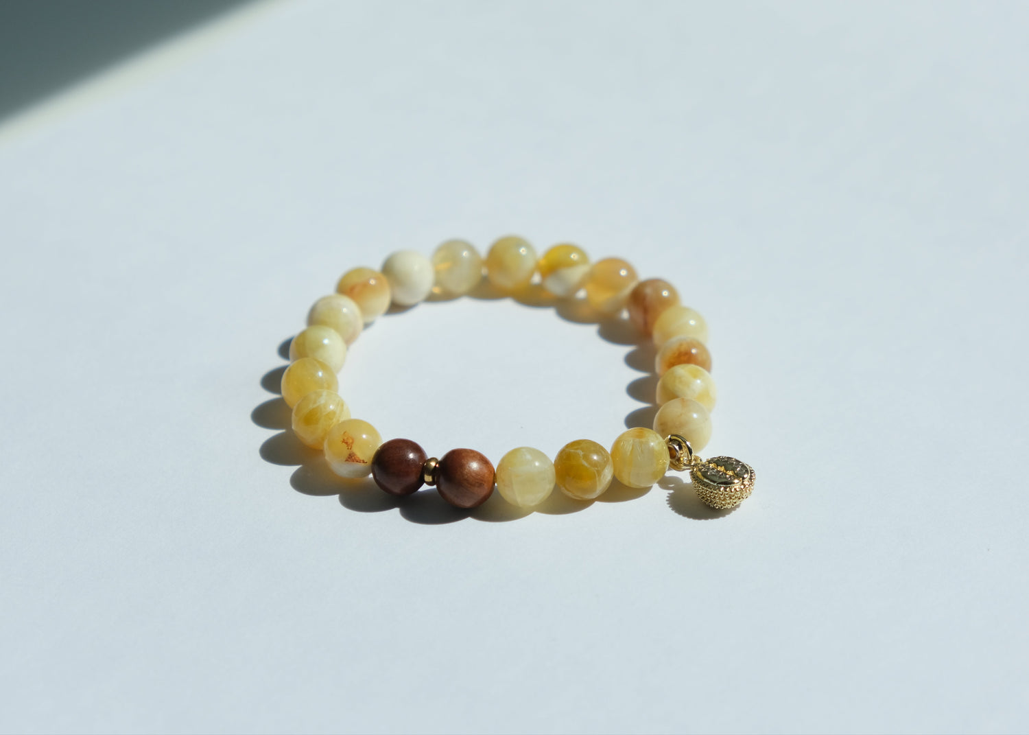 Beaded bracelet with a gold charm on a white background