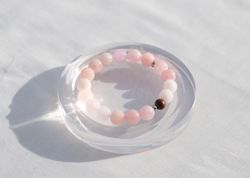 Pink beaded bracelet on a clear dish with a white background