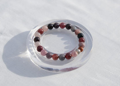 Multicolored beaded bracelet on a clear stand against a white background