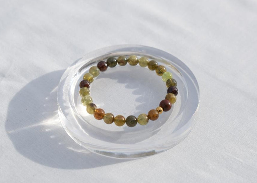 Multicolored beaded bracelet on a clear stand against a white background