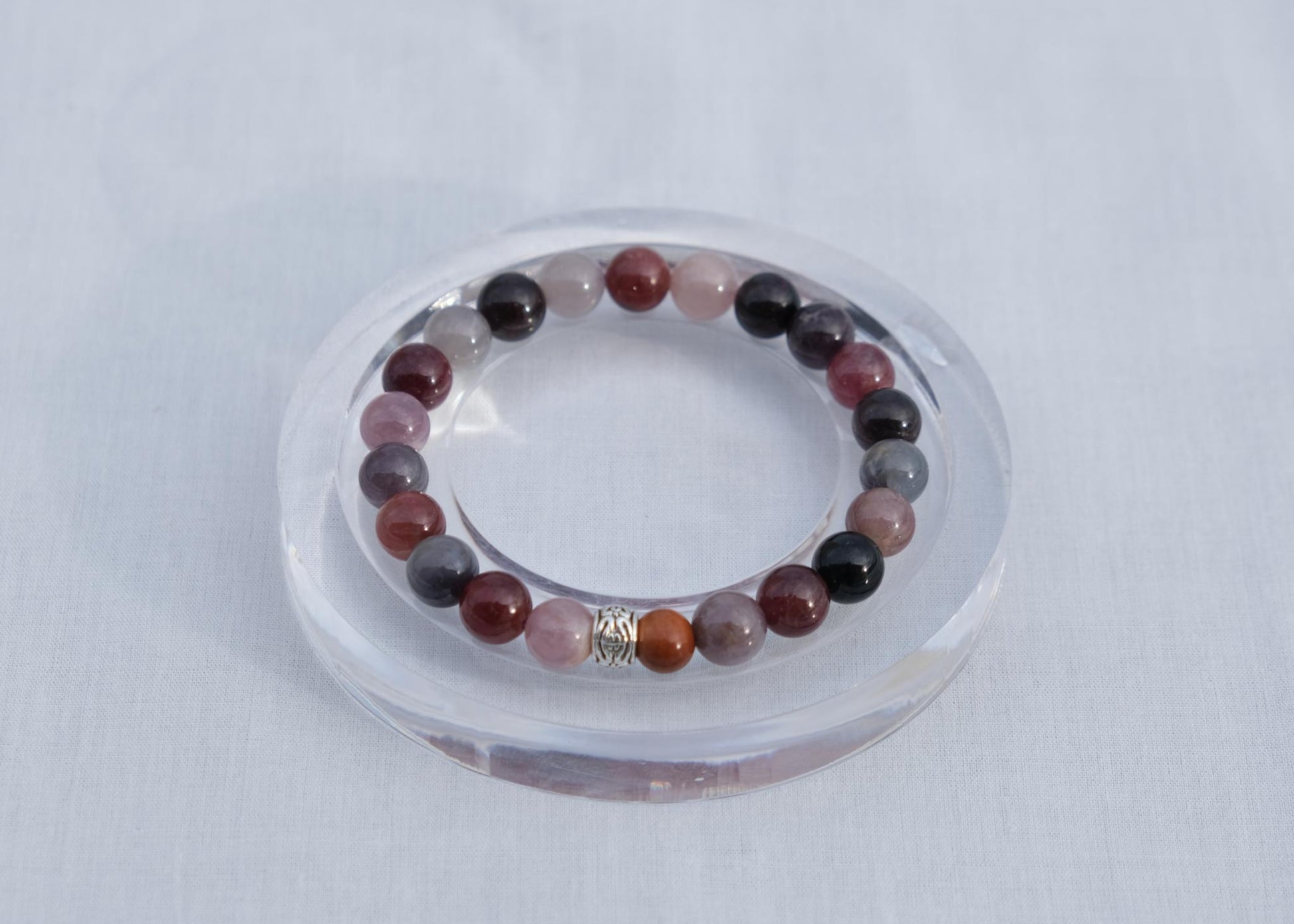Multicolored beaded bracelet on a clear stand against a light gray background