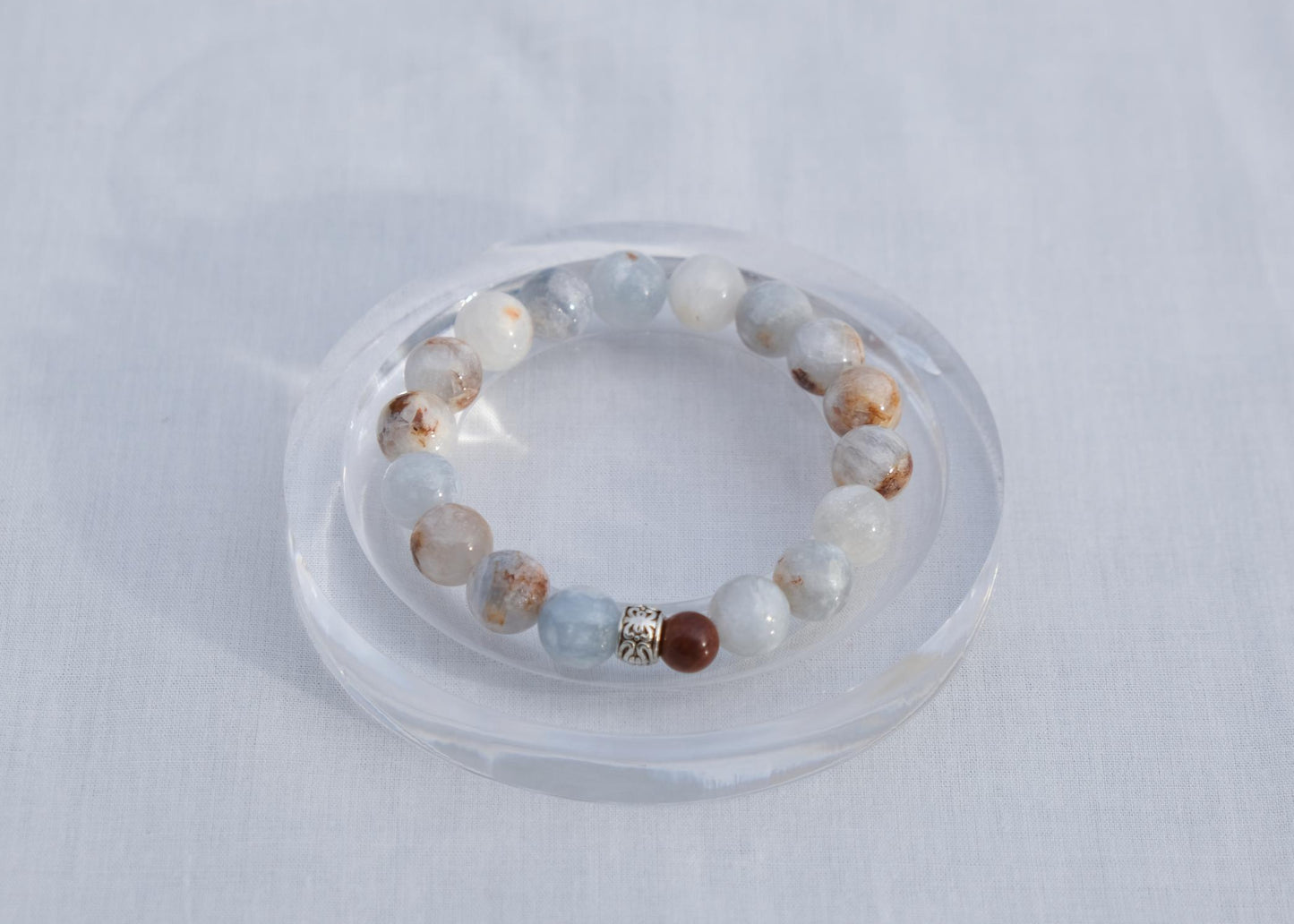 Beaded bracelet on a clear stand against a light gray background