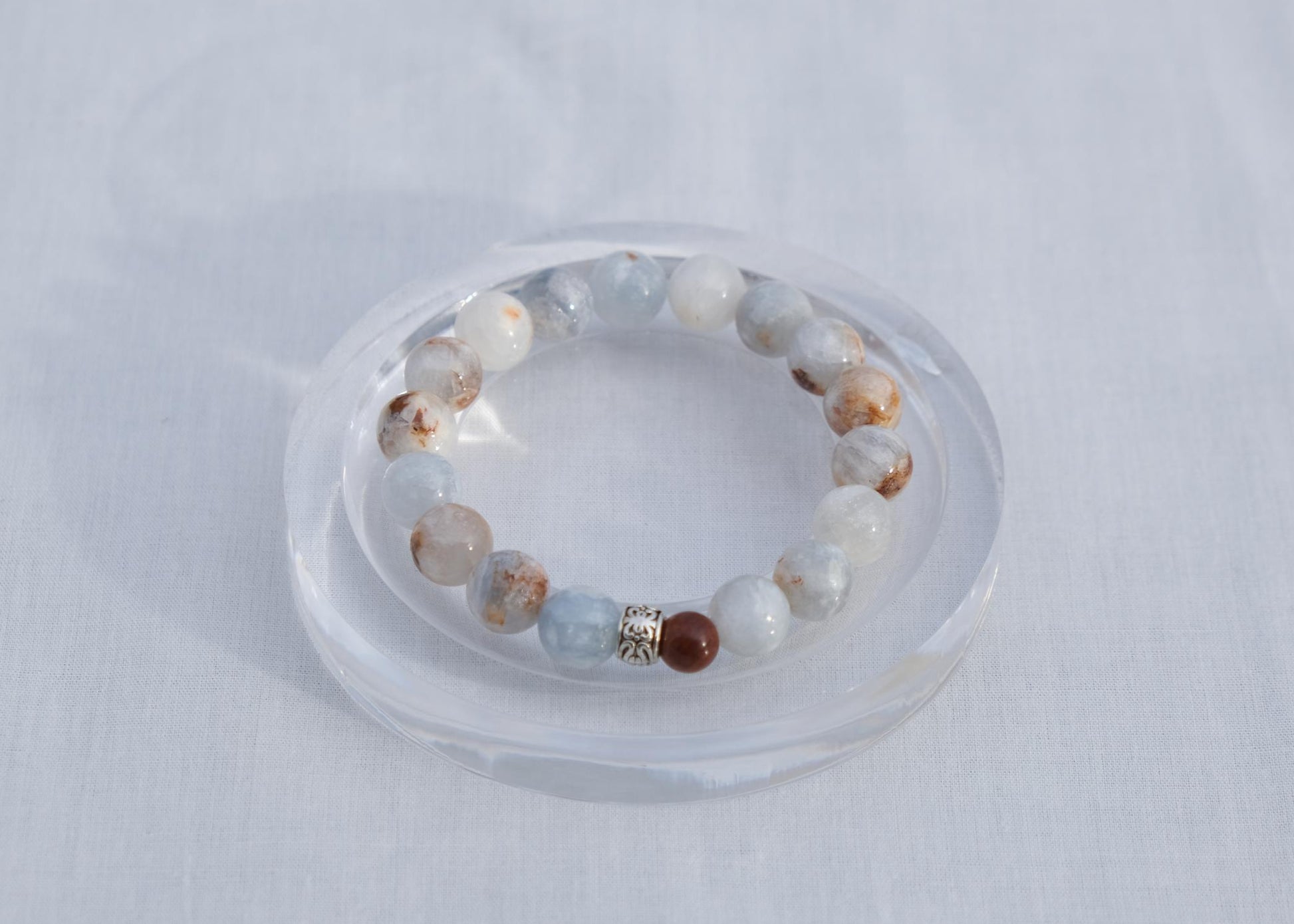 Beaded bracelet on a clear stand against a light gray background