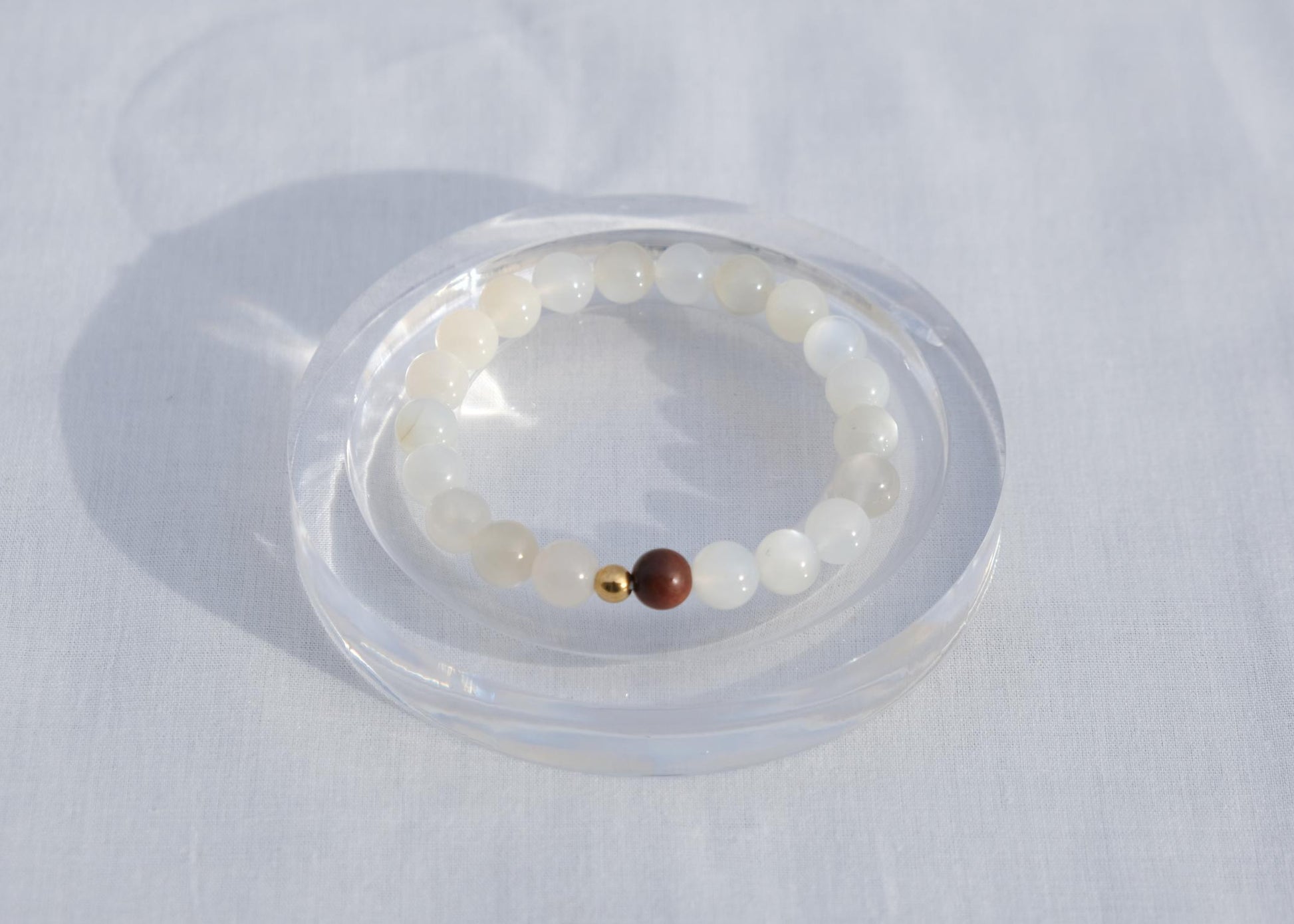 Bracelet with white beads and a brown bead on a white background