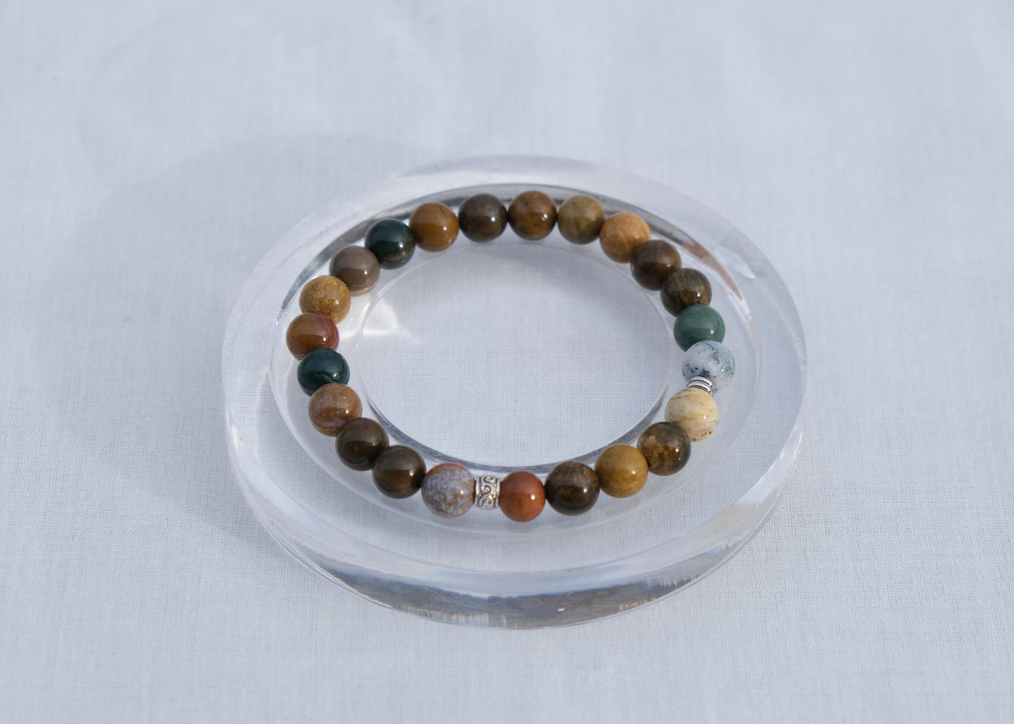 Multicolored beaded bracelet on a clear stand against a white background