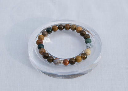 Multicolored beaded bracelet on a clear stand against a white background