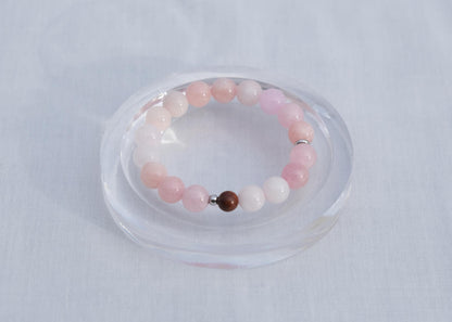 Beaded bracelet with pink and white beads on a clear stand against a light gray background