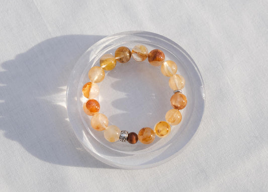 Crystal bracelet on a white surface with a clear plastic cup underneath